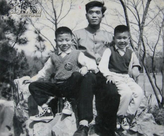 文革老照片:戴像章,父亲与他的两个儿子坐在假山上