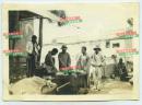 1935年5月29日河北石家庄元氏县城墙下卖烟卷杂货的小摊贩老照片，有一些男人围拢购买。8.7X6.2厘米