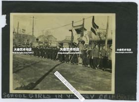 西德尼∙D∙甘博拍摄1918年北京师范大学附属中学女学生在崇文门大街游行老照片，中国作为胜利国庆祝一次世界大战结束，可见“相显像馆”照相馆，青林堂东洋点心馆等，到处都飘扬着北洋政府五色旗。10.7X8.2厘米，泛银。 来自甘博的朋友, 沪江大学教授普天德博士（Dr.Gordon Poteat ）收藏。
