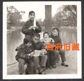 五六十年代，一位织着毛衣的母亲和四个孩子的游园，看书玩玩具枪，非常祥和的画面