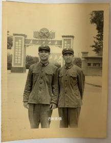 【老照片】1973年两士兵于兰州军区大门前留念（见背题）--- 大门上有：五角星，为人民服务，左侧标语是“领导我们思想的理论基础是马克思列宁主义”； 很有时代特色，（ 尺寸：8.7×11.2cm）。