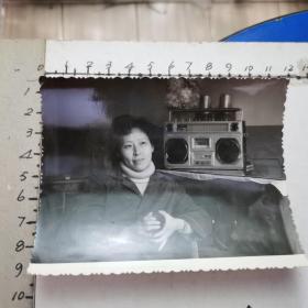 老照片：端玻璃杯、悠闲听磁带的女青年（烫发、双喇叭单卡放音机、80年代、尺寸：11.3×9cm）
