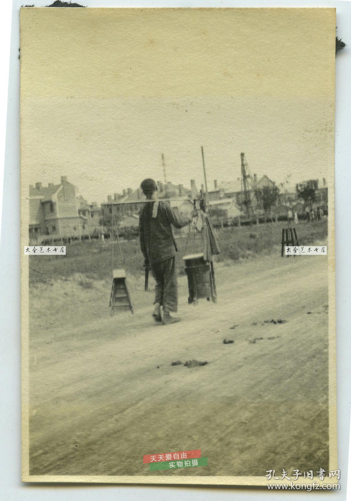 民国时期天津的一名剃头匠担着挑子背影老照片,附近是美国兵营一带,泛